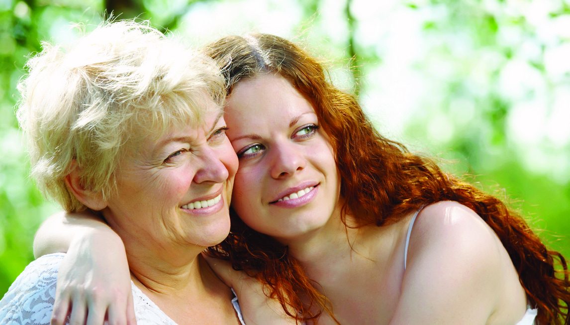 An older woman and her daughter sharing a hug outdoors