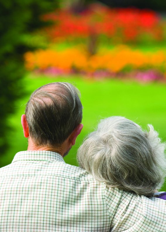 A couple sitting together, looking out over a flower garden